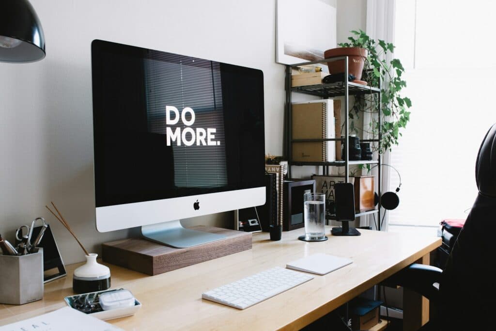 A tidy home-office desk with a desktop monitor reading "Do more."